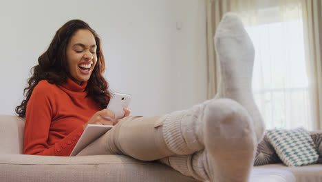 Frau-Sitzt-Lachend-Auf-Dem-Sofa-Und-Benutzt-Ihr-Mobiltelefon-4k-4k