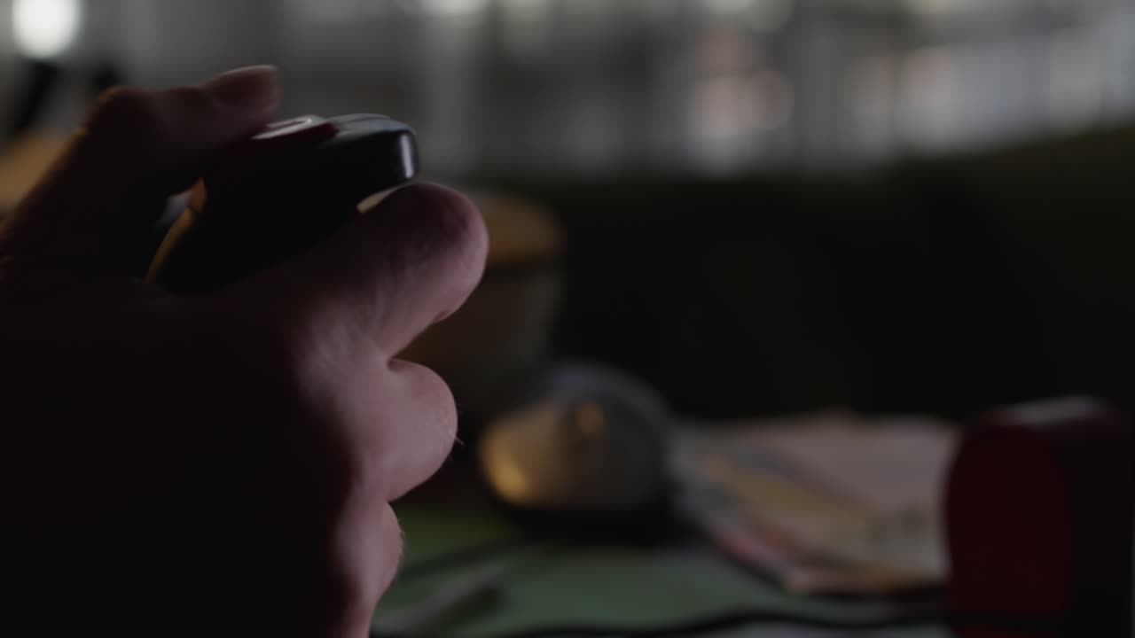 A hand furiously moves the joystick in the heat of the game in the light of the TV screen