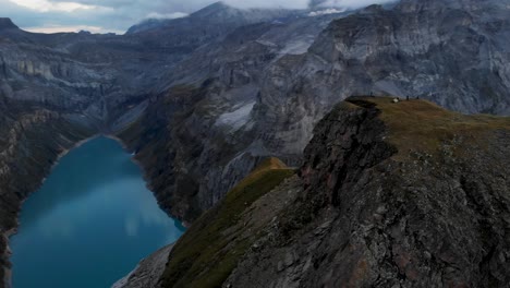 un paso elevado sobre un mirador de limernsee en glarus, suiza, con excursionistas disfrutando de la vista de los acantilados de los alpes suizos, el paisaje y el lago desde su lugar de campamento
