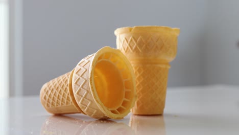 man picking up ice cream cone on a white table