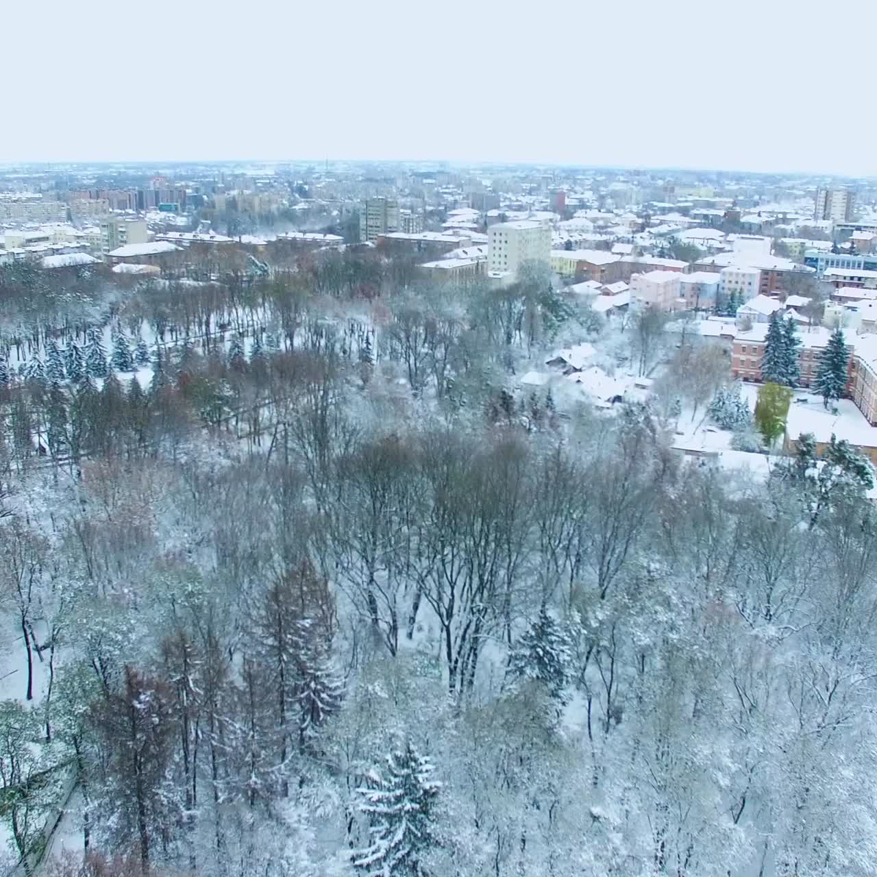 City in snow on winter season. Beautiful urban panorama with buildings, parks and roads from top view