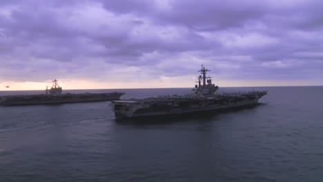 aerial over two aircraft carriers on the high seas with helicopter moving between 1