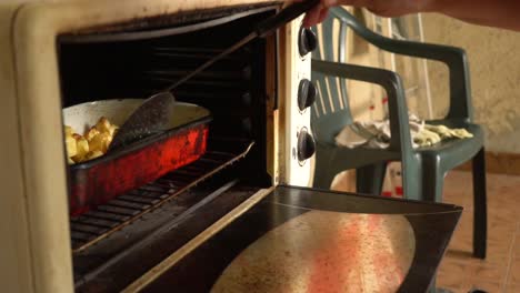 baker's hand using perforated spatula in cooking dish in the oven