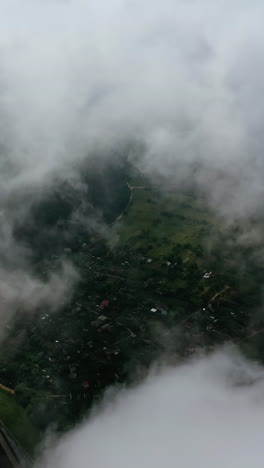 light clouds moving in the sky. city view from the air through white clouds. flying over the river and country. aerial view. vertical video