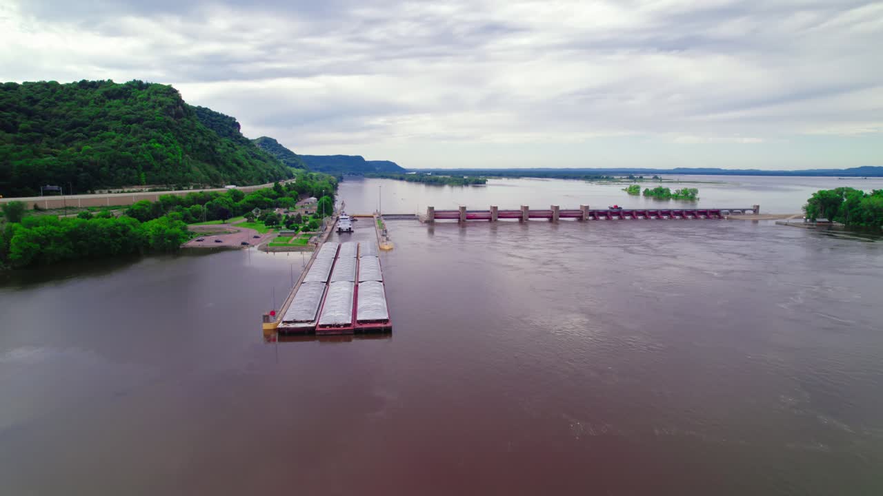 Establisher aerial of tugboat approaching barge boat that is passing through the lock and dam system near La Crescent, Minnesota, on the Mississippi River. USA