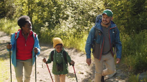 cheerful multiracial family hiking with trekking poles