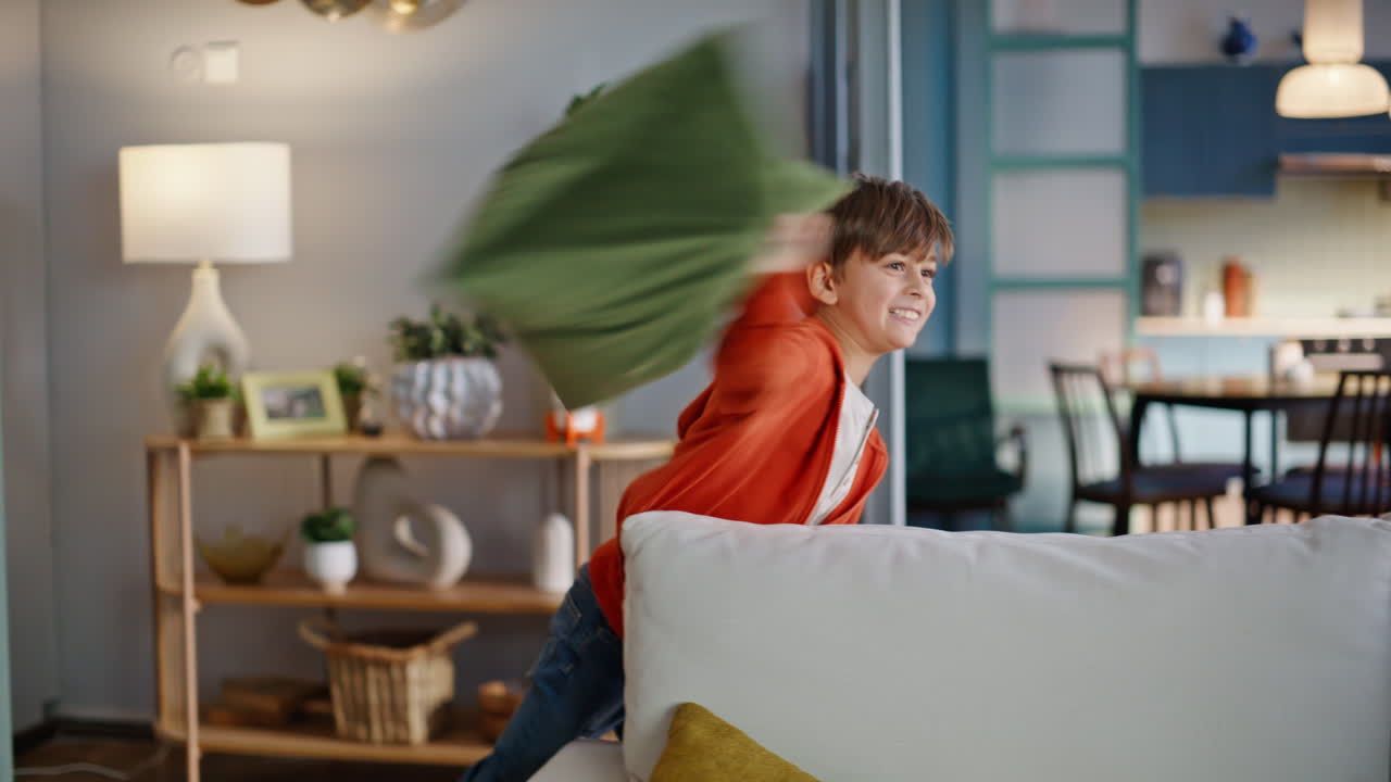 Happy father playing funny game son home. Smiling man fighting pillows boy