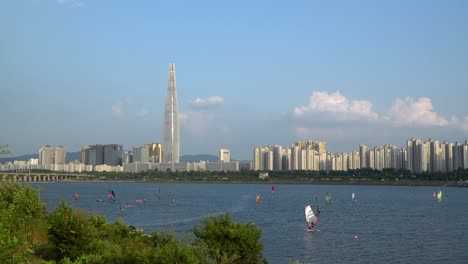 Gente-Haciendo-Windsurf-En-El-Río-Han-En-Un-Día-Soleado-De-Verano,-Torre-De-Lotería-En-El-Fondo