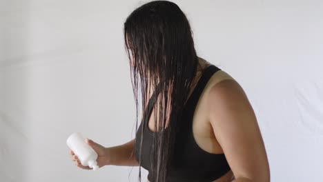 hispanic adult woman applies cream for hair hydration treatment