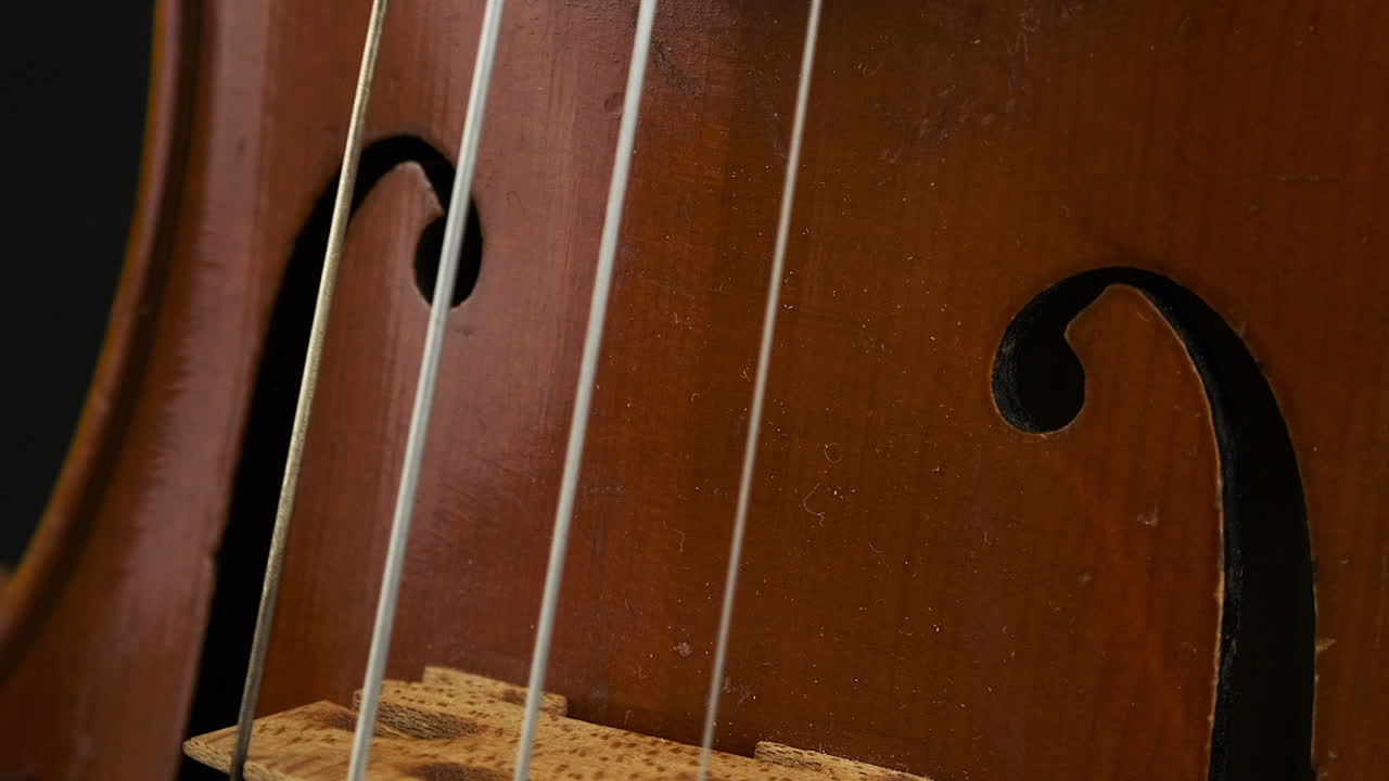 Extreme close up view of violin body, F holes rotating in dark room