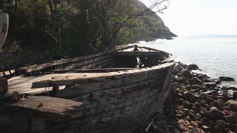 dolly-shot-of-an-old-wooden-boat-abandoned-on-the-coast-in-tropical-waters