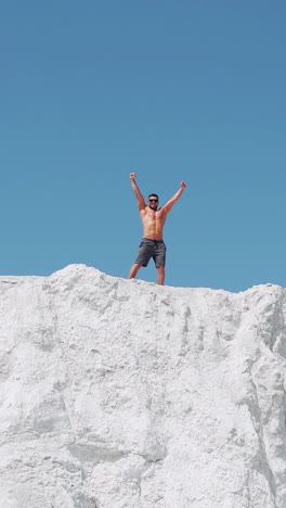 the athlete joyfully celebrates the victory with his hands up. running athlete on top of the mountain. vertical video