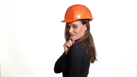 beautiful woman in orange helmet and black golf is poses for the camera on a white background in the studio.