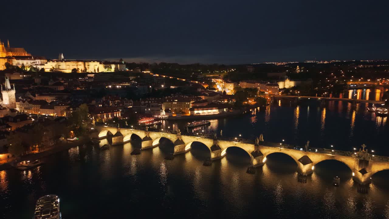 Aerial night view of Charles Bridge and Prague Castle over Vltava River, Czech Republic