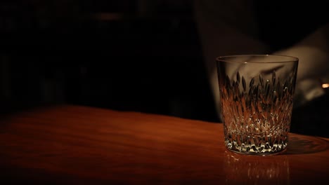 empty glass sits on a polished wooden surface.