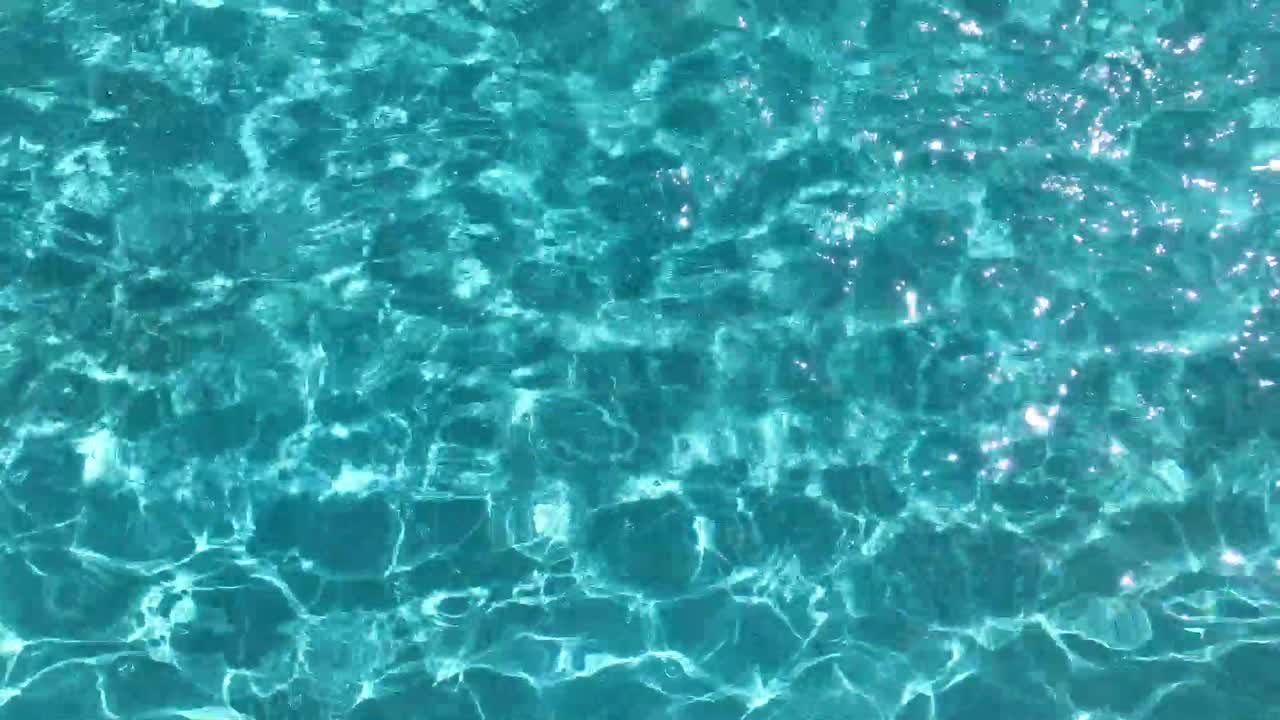 Permukaan air beriak di kolam renang. Latar belakang permukaan air biru.