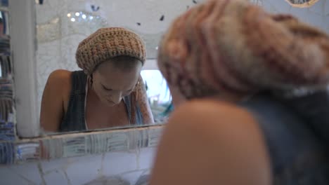 a young, alternative woman with tattoos is holding her arms over her head while looking at her reflection in the mirror