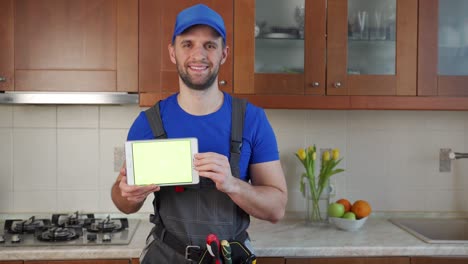 el fontanero sostiene una tableta digital con una pantalla verde en la cocina
