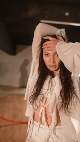 woman in white clothing, posing in a studio setting