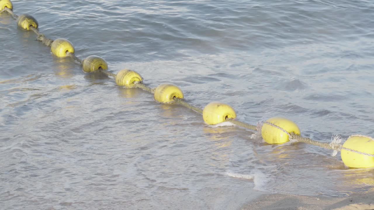 A secured rope with yellow sea buoy’s floating on a coastal beech, the buoy’s used to demarcate a safe bathing area in Pattaya, Chon Buri, Thailand