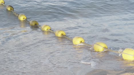 a secured rope with yellow sea buoy’s floating on a coastal beech, the buoy’s used to demarcate a safe bathing area in pattaya, chon buri, thailand