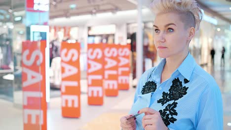 woman shopping in a mall, holding credit card