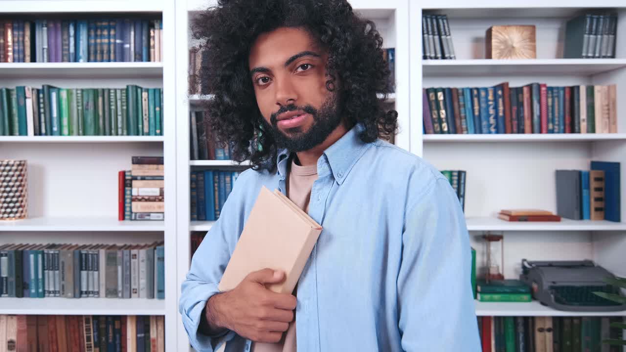 Young attractive indian man student posing for camera with book