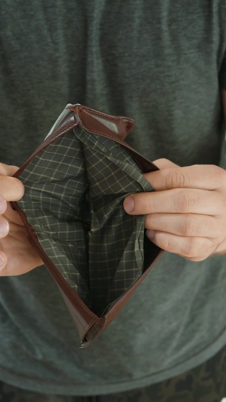 Close-up of a man opening an empty wallet, symbolizing no money, financial problems, poverty, cash shortage, personal budget stress, and economic hardship.
