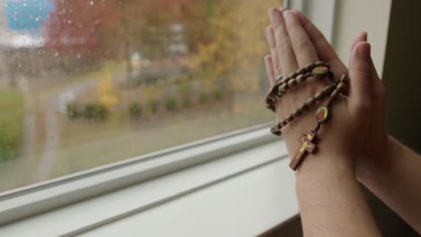 Close-Up-Tilt-of-Hands-in-Prayer-Holding-Rosary-Beads