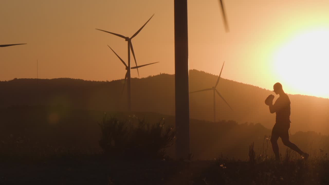 Athlete at sunset trains with a kettlebell lifting it up. Silhouette shooting. The concept of environmentally friendly energy