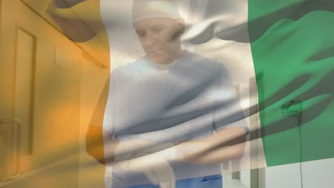 animation of flag of ivory coast, caucasian surgeon adjusting gloves and rushing to operation room