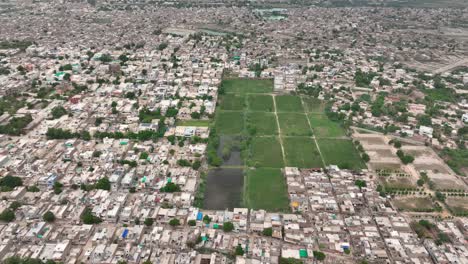 Toma-Aérea-Panorámica-De-Una-Zona-Urbana-Con-Un-Campo-Verde