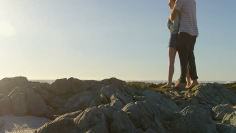 una joven pareja romántica abrazándose en una roca en la playa 4k