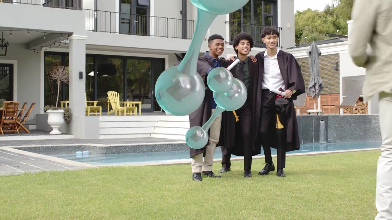 Laureati che escono dal patio verso il prato in posa con i diplomi, molecole AR che fluttuano tra la fotocamera e il gruppo
