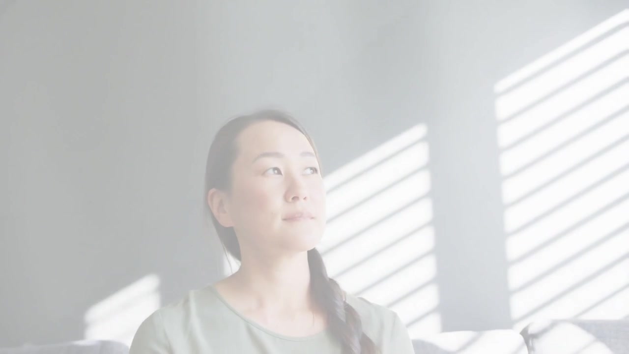 縦型動画：妨害が解消されるのに気づき、ソファに座った韓国人女性がブラインドの方に目を向ける。