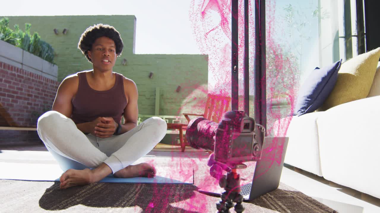 Coach teaching fitness on mat, laptop emitting pink orbs rising past camera and drifting near coach