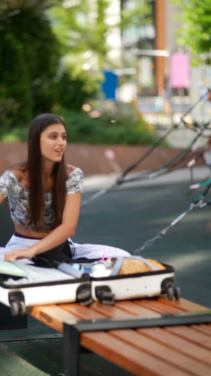 una mujer joven empacando una maleta en un parque de la ciudad