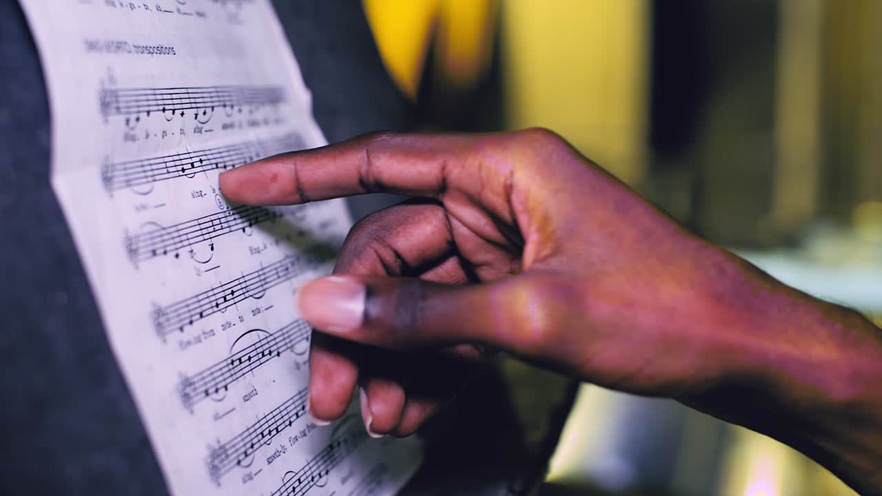 Close up of a African American hand pointing to sheet music on a stand