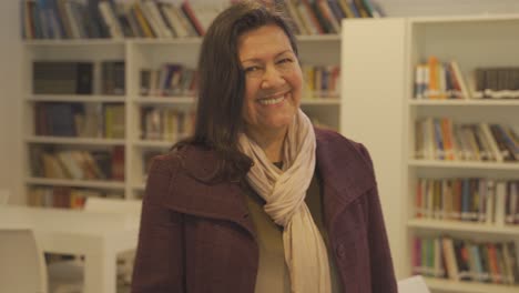 Portrait-of-happy-middle-aged-woman-smiling-into-camera-standing-inside-Library---4K-30fps