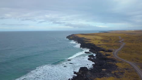 Aerial-view-of-waves-slamming-against-black-rock-cliffs
