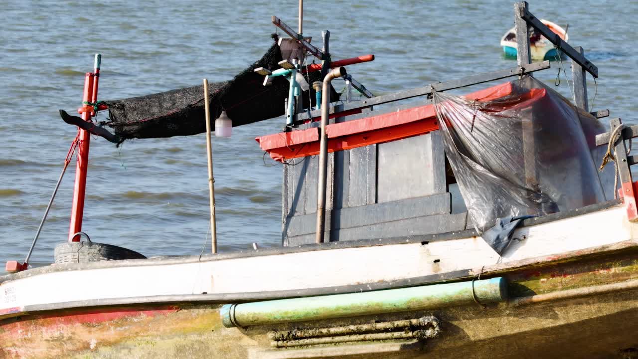 Detailed view of a fishing boat's structure and equipment against a calm water backdrop.