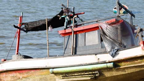 detailed view of a fishing boat's structure and equipment against a calm water backdrop.