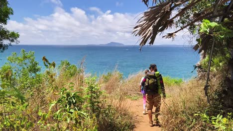 family hiking along a tropical beach path