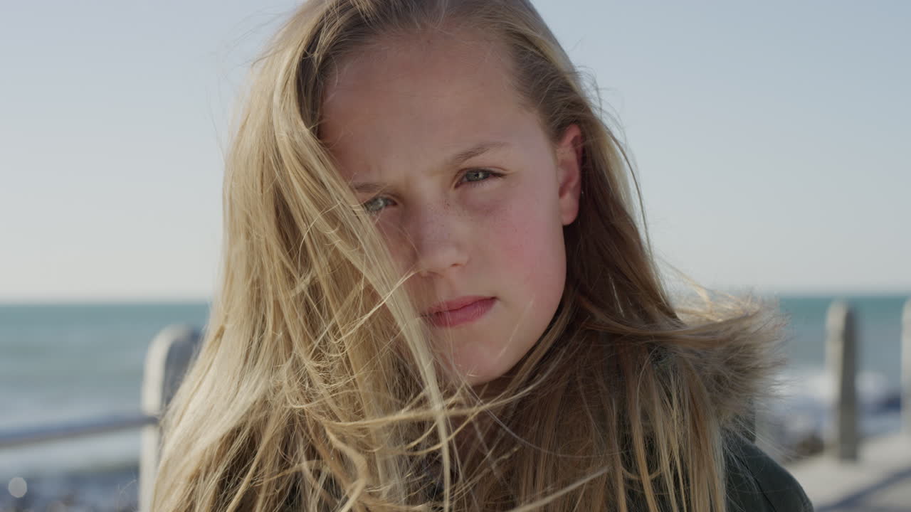 초상화 귀여운 작은 카카오시안 소녀 심각한 아름다운 긴 머리카락 바 ⁇ 가 해변에서 바람에 불어 느린 동작 클로즈업