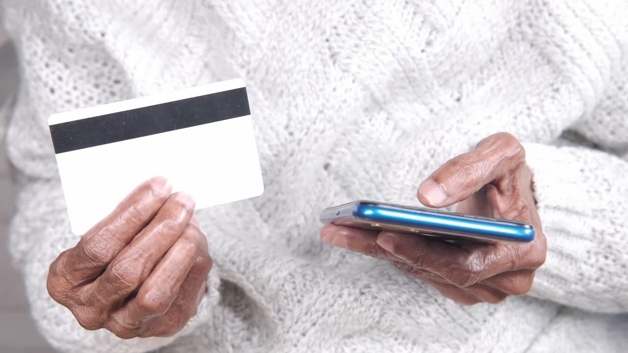 Persona anziana che usa smartphone e carta di credito per il pagamento online