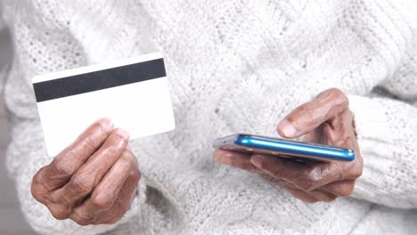 elderly person using smartphone and credit card for online payment