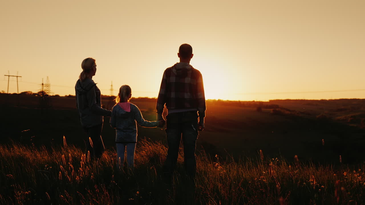 una familia de tres personas se encuentra con el amanecer en un lugar pintoresco en la montaña
