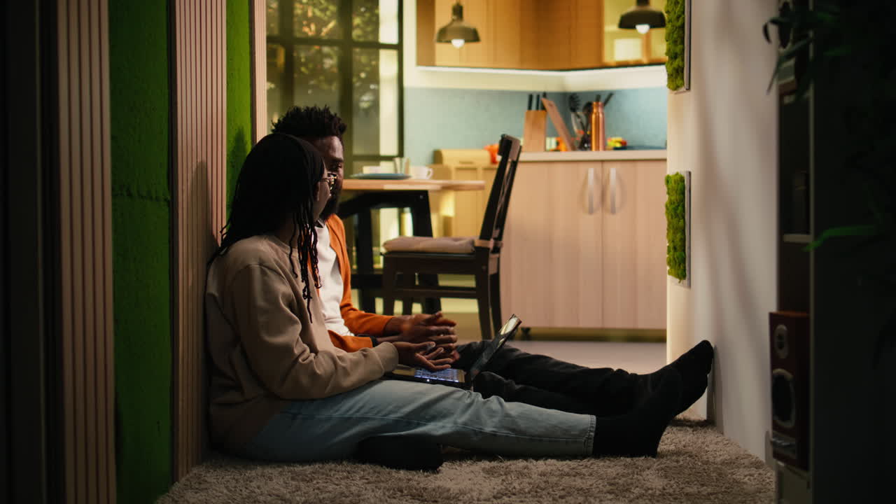 African American couple solving remote tasks together on the floor