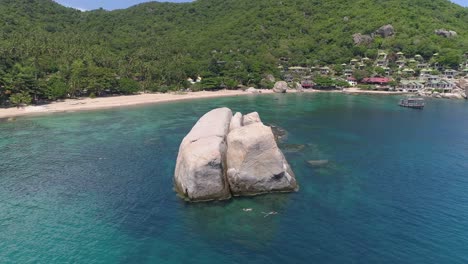 beautiful tropical beach with clear water and a large rock in the middle