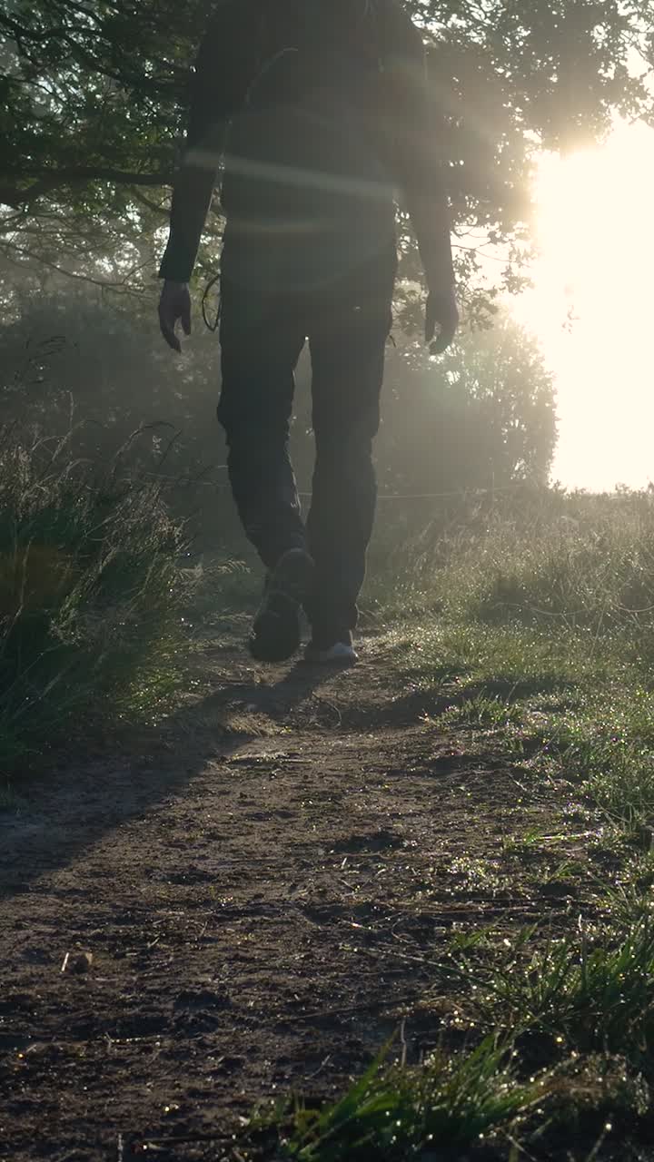hombre caminando a través del bosque de niebla al amanecer